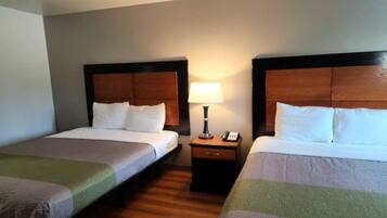 A hotel room with two single beds, a nightstand with a lamp, and a telephone.