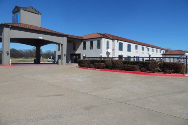 A building with a covered entrance, a satellite dish, and a red curb. - 2 Queen Beds | Non-Smoking (Ennis)
