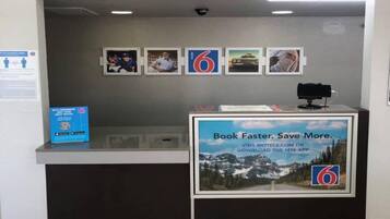 A reception desk with a sign promoting a mobile app, framed pictures on the wall, and a QR code for membership.