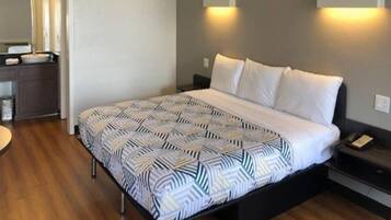 A hotel room with a bed, bedside tables, a desk, and a mirror.