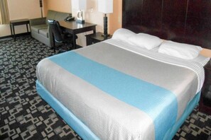 A hotel room with a bed, a desk, a chair, and a lamp. - 1 King Bed | Non-Smoking, Micfridge (JOSHUA)
