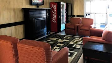 Eine Lobby mit Kamin, roten Sesseln, einem gemusterten Teppich und einem Coca-Cola-Kühlschrank.