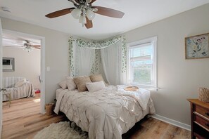 A bedroom with a bed, a ceiling fan, a window with curtains, and a wooden dresser. - Lakefront Unit w/ Views, Near Colleges & Hospitals (Worcester)