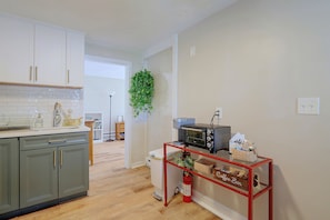 Een moderne keuken met witte kastjes, een houten aanrecht en een hangplant.
