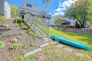 A residential area with a wooden staircase leading to a porch, a blue canoe, and a grassy yard. - Lakefront Unit w/ Views, Near Colleges & Hospitals (Worcester)