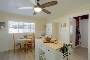 A kitchen with a ceiling fan, a dining table with chairs, a wooden cabinet, and a window with blinds. - McCloud Retreat Near Mt Shasta & Waterfalls! (McCloud)