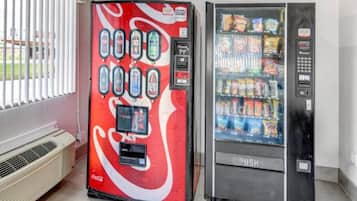 Un distributeur automatique arborant le logo Coca-Cola et doté d’un panneau de commande à boutons, ainsi qu’un présentoir réfrigéré contenant des en-cas.