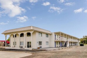 A motel with a central building and attached wings, featuring a flat roof, multiple windows, and a parking lot. - 2 Queen Beds | Smoking (Waco)