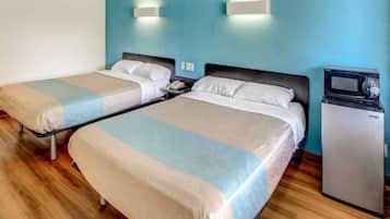 Two single beds with wooden frames, a small bedside table with a lamp, and a microwave on the wall.