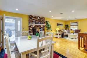 A dining area with a white table and chairs, a brick wall with a shelf, and a yellow wall. - 1 Mi to Colonial Beach! Coastal Escape w/ Fire Pit (Colonial Beach)