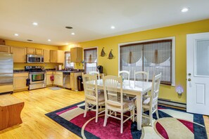A compact kitchen with modern appliances, a dining area with a table and chairs, and a yellow wall. - 1 Mi to Colonial Beach! Coastal Escape w/ Fire Pit (Colonial Beach)