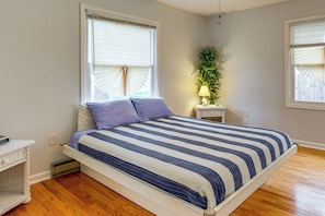 A bedroom with a bed, a nightstand, a lamp, and a potted plant. - 1 Mi to Colonial Beach! Coastal Escape w/ Fire Pit (Colonial Beach)