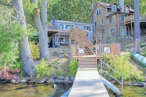 A wooden bridge leading to a house with a stone foundation, surrounded by trees and a stream. - Big Alum Pond Escape w/ Dock & Fire Pit! (Sturbridge)