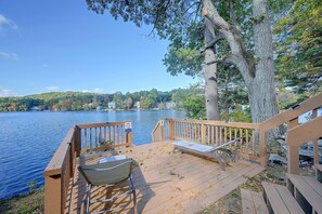 A wooden deck with a bench and a chair overlooking a lake, surrounded by trees. - Big Alum Pond Escape w/ Dock & Fire Pit! (Sturbridge)