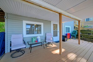 A covered outdoor seating area with two chairs, a table, and a small television. - Big Alum Pond Escape w/ Dock & Fire Pit! (Sturbridge)