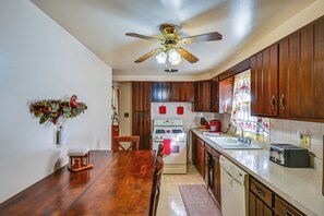 A kitchen with wooden cabinets, a white stove, and a ceiling fan. - 1 Mi to Notre Dame & Dtwn: Charming Home w/ Yard (South Bend)