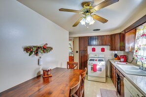 A kitchen with wooden cabinets, a stove, a refrigerator, and a dining table with chairs. - 1 Mi to Notre Dame & Dtwn: Charming Home w/ Yard (South Bend)