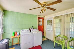 Une buanderie équipée de deux machines à laver, d’un ventilateur de plafond et d’une chaise verte.