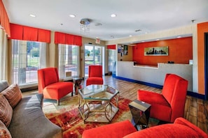A hotel lobby with red chairs, a glass coffee table, and a reception desk. - Spacious 1 KING BED | NON-SMOKING (ARLINGTON)