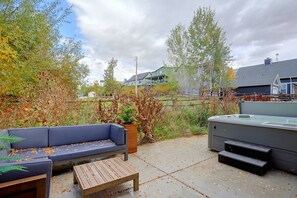 An outdoor patio area with a blue sofa, a wooden table, and a hot tub. - 4 Mi to Slopes! Eden Home w/ Private Hot Tub (Eden)