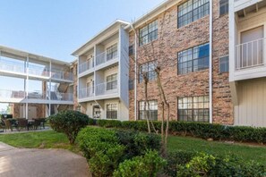 A multi-story building with a brick facade, balconies, and a covered outdoor seating area. - 2 Full Beds |Suite,Nsmk,Kitchen (Arlington)