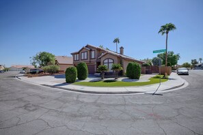 A residential house with a well-maintained lawn, a driveway, and a street sign indicating the address. - Patio & Grill! Spacious Las Vegas Oasis (Las Vegas)