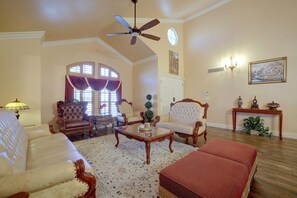 A spacious living room with a ceiling fan, a fireplace, and a large window with curtains. - Patio & Grill! Spacious Las Vegas Oasis (Las Vegas)
