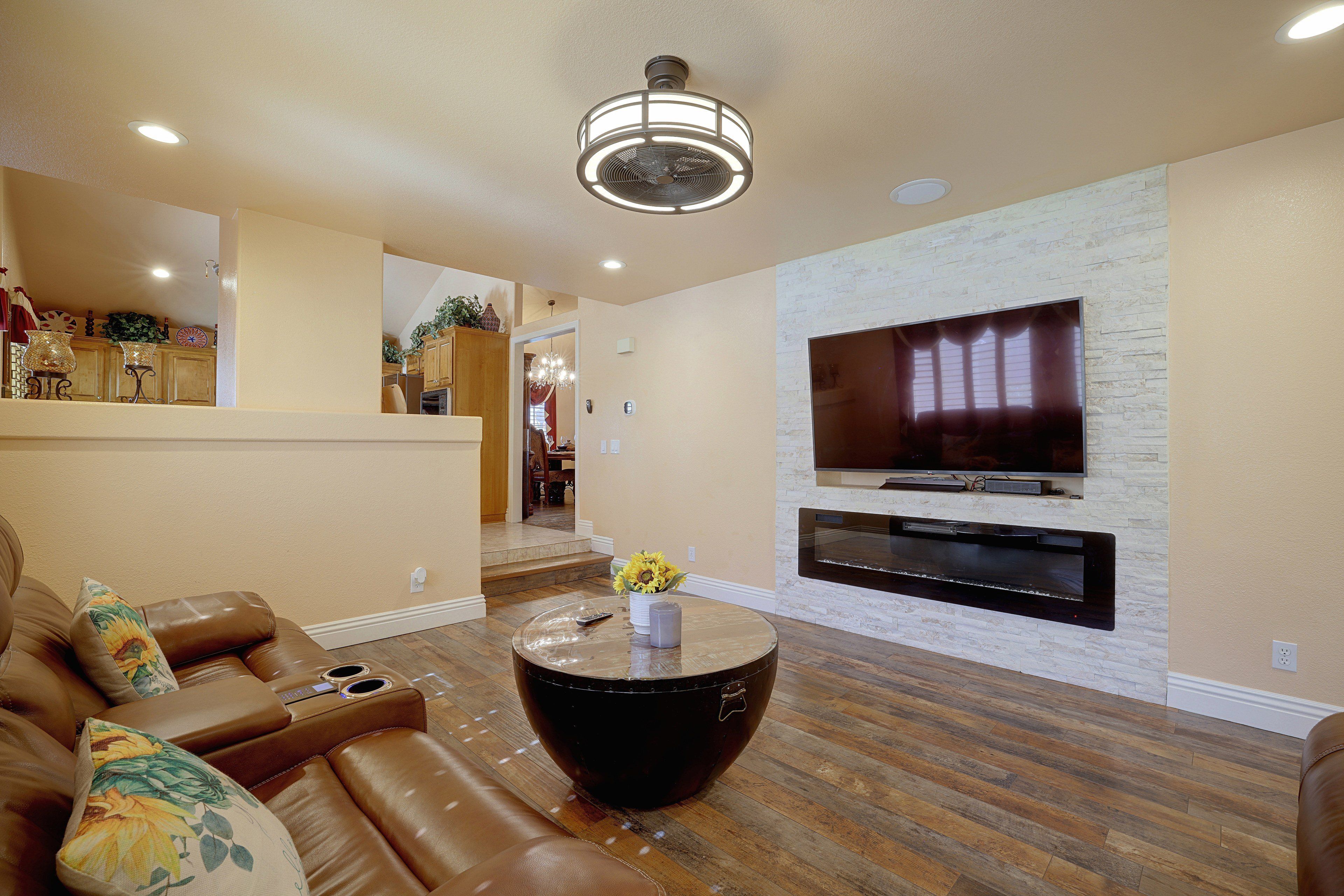 A living room with a leather sofa, a coffee table, a fireplace, and a television mounted on a stone wall.
