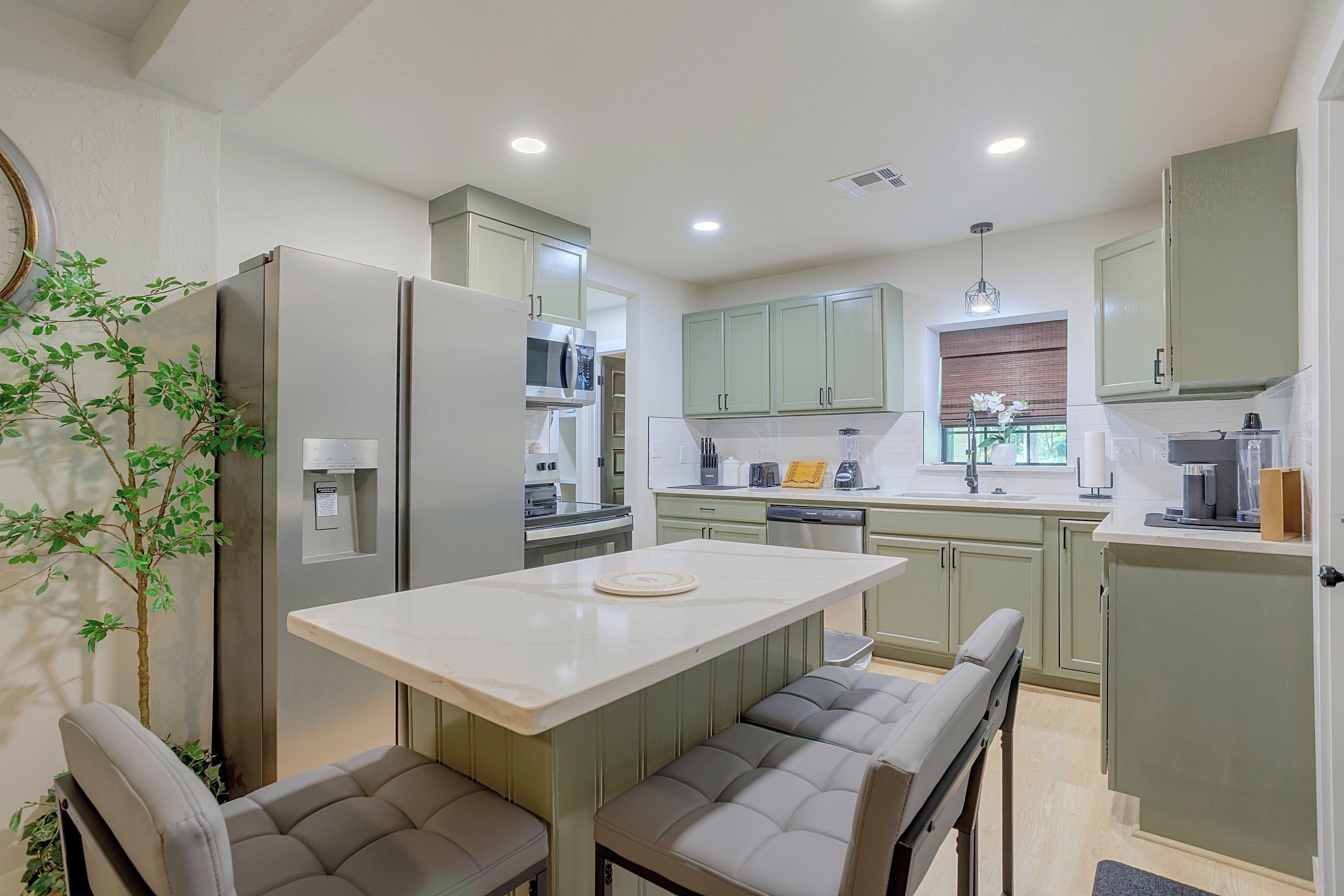 A modern kitchen with a central island, seating, and built-in appliances.