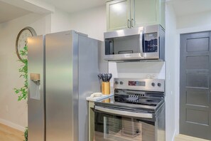 A modern kitchen with stainless steel appliances, including a refrigerator, microwave, and oven. - Guthrie Home in the Heart of Historic Downtown! (Guthrie)