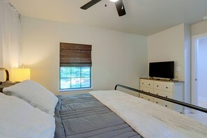 A bedroom with a bed, a television on a dresser, a window with blinds, and a ceiling fan. - Guthrie Home in the Heart of Historic Downtown! (Guthrie)