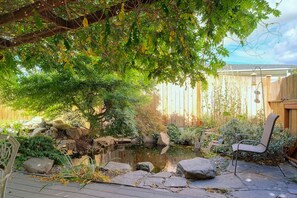 Une terrasse en bois avec un bassin, des rochers et une chaise.