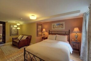 Une chambre d’hôtel avec un lit, un canapé, une table de chevet et un tableau au mur.