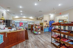 Ein gut beleuchteter Kiosk mit einer Auswahl an Produkten, darunter Snacks und Getränke, und einem sichtbaren Ausgangsschild.