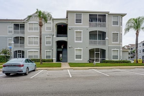 A multi-story residential building with a parking lot in front. - Resort Perks! Family Condo 4 Mi to Disney World! (Kissimmee)