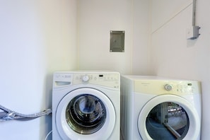 Two front-loading washing machines in a laundry room with a white wall and a metal vent. - 6 Mi to the Masters: North Augusta Condo (North Augusta)