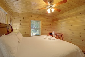 A wooden room with a bed, a window, and a ceiling fan. - Hot Tub, Fire Pit, Views & More: Blowing Rock Gem (Blowing Rock)