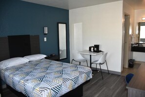 A hotel room with a bed, a desk with a chair, a coffee maker, and a mirror. - 1 Full Bed | Non-Smoking, Kitchen (Grand Prairie)