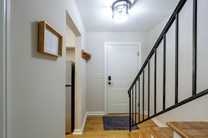 A hallway with a wooden door, a framed picture on the wall, and a staircase with a black railing. - Duplex 6 Miles to downtown Augusta (North Augusta)