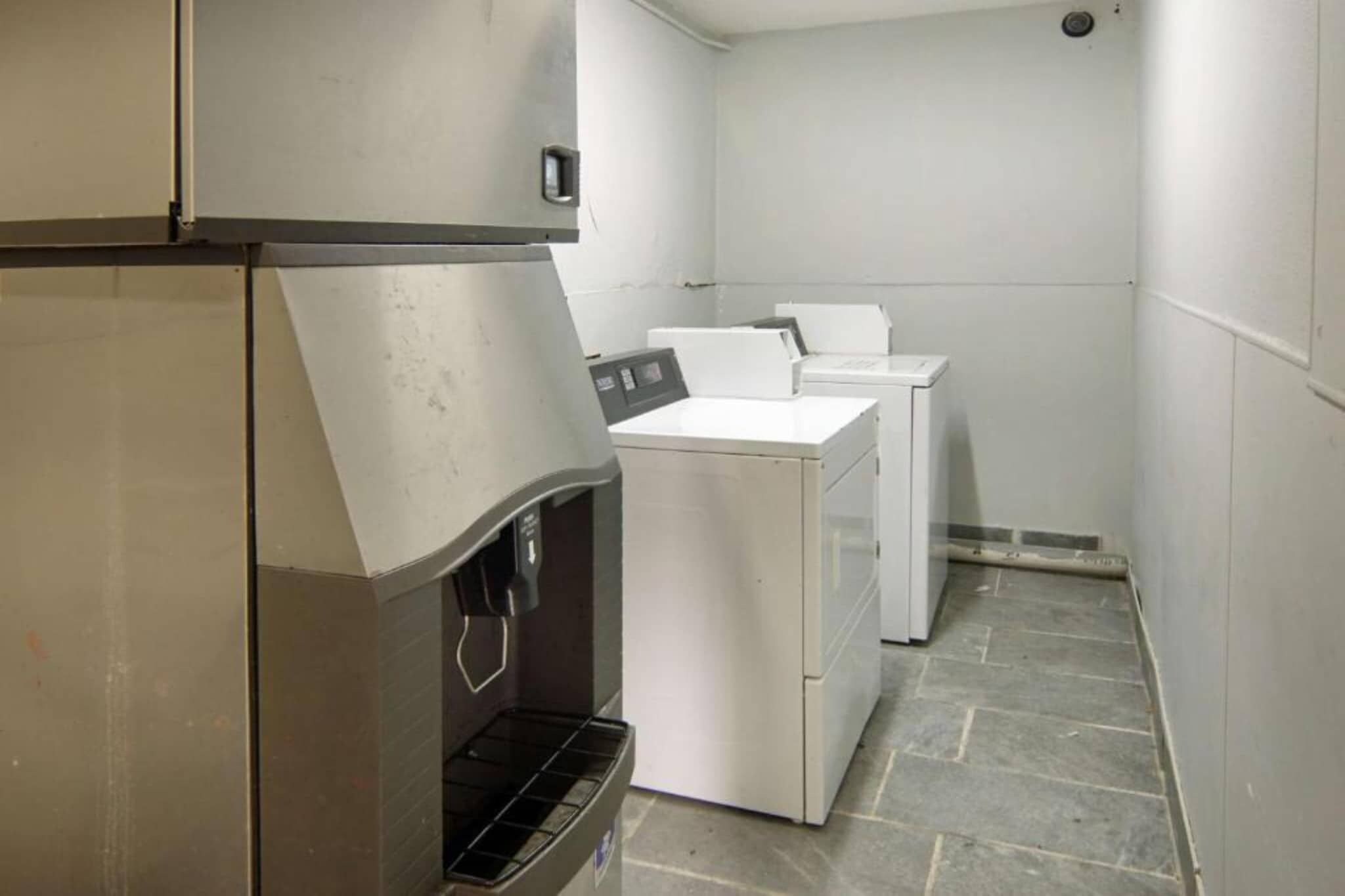 A laundry room with a stainless steel refrigerator, a washing machine, and a dryer.