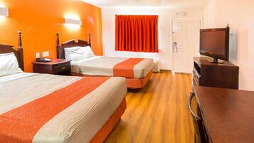 A hotel room with two beds, a television, and a door.