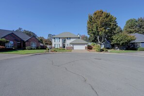 A residential street with houses, a driveway, and a large tree. - Lovely, Spacious Gem: Walk to Autzen & River Trail (Springfield)