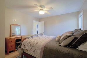 A bedroom with a bed, a dresser, a mirror, and a ceiling fan. - Lovely, Spacious Gem: Walk to Autzen & River Trail (Springfield)