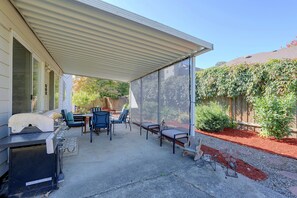 Eine überdachte Terrasse mit Gartenmöbeln, einem Grill und einem von Mückennetzen geschützten Bereich.