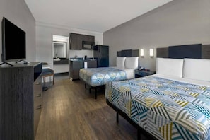 A hotel room with a bed, a desk, a chair, a television, a kitchenette, and a bathroom. - 2 Full Beds | Smoking (DENTON)