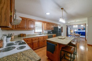 A kitchen with wooden cabinets, granite countertops, a built-in stove, and a refrigerator. - Murray Retreat w/ Game Room (Murray)