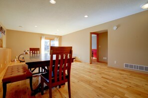 A spacious room with a dining table and chairs, wooden flooring, and a ceiling with recessed lighting. - Northfield Home Near Nerstrand Big Woods (Northfield)