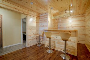 Ein Holzinterieur mit Barbereich, zwei Barhocker und einer Pendelleuchte.
