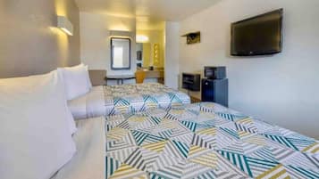 Ein Hotelzimmer mit Bett, Schreibtisch, Fernseher und Spiegel.