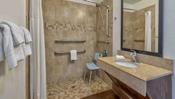 Ein Badezimmer mit Dusche, Waschbecken, Stuhl und Handtuchhalter.